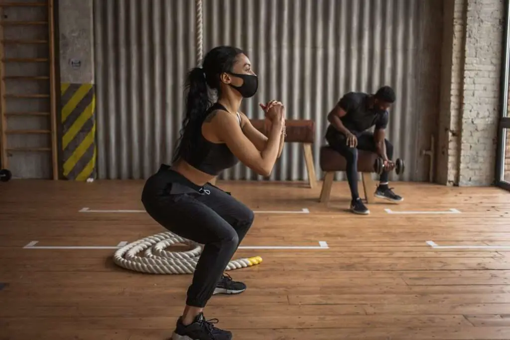 woman in mask doing squats